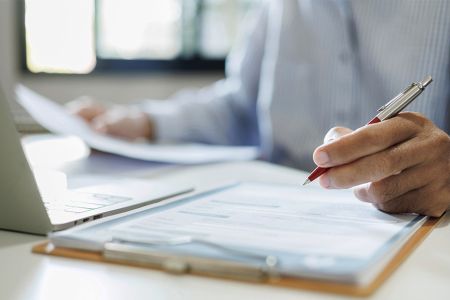 Foto: Person mit Dokumenten und Laptop