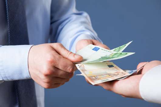 Foto: zwei Hände übergeben Geldscheine in eine dritte Hand