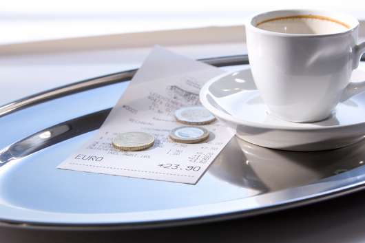 Foto: Trinkgeld auf Tablett mit leerer Kaffeetasse